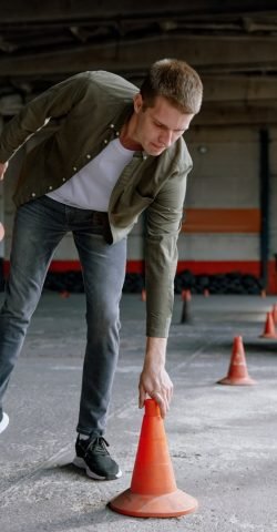 Motorbike driving school lesson with instructor putting cone on track Motorbike driving school lesson with instructor putting cone on track front of student. Indoor motodrome training center